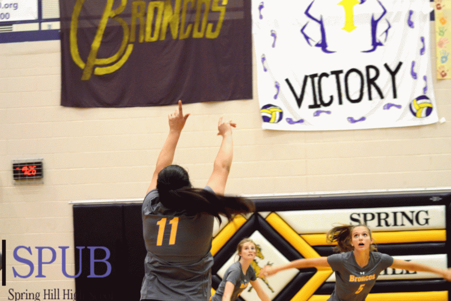 Danielle Gonzalis, 11, sets the ball for Alli Frank, 11, to spike over the net. The mid air moment also shows the many decorative banners hung for the Lady Broncos that day.