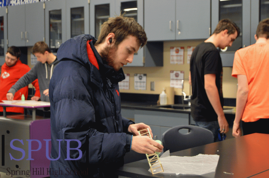 While fixing his bridge during his second hour Engineering Applications class on Nov. 12, Kyler Breinholt, 11, adds glue to the structure to make it sturdier. He explained that he didnt think it would hold with what he had done already (Photo by E. Dowd).