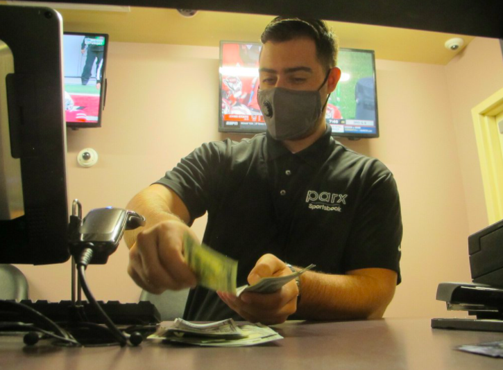 A clerk at the Freehold Raceway in Freehold, N.J. counted money in the sports betting lounge. Due to the ongoing pandemic, and the resulting financial situations of many Americans, betting is supposed to fall dramatically this year (photo courtesy AP News).