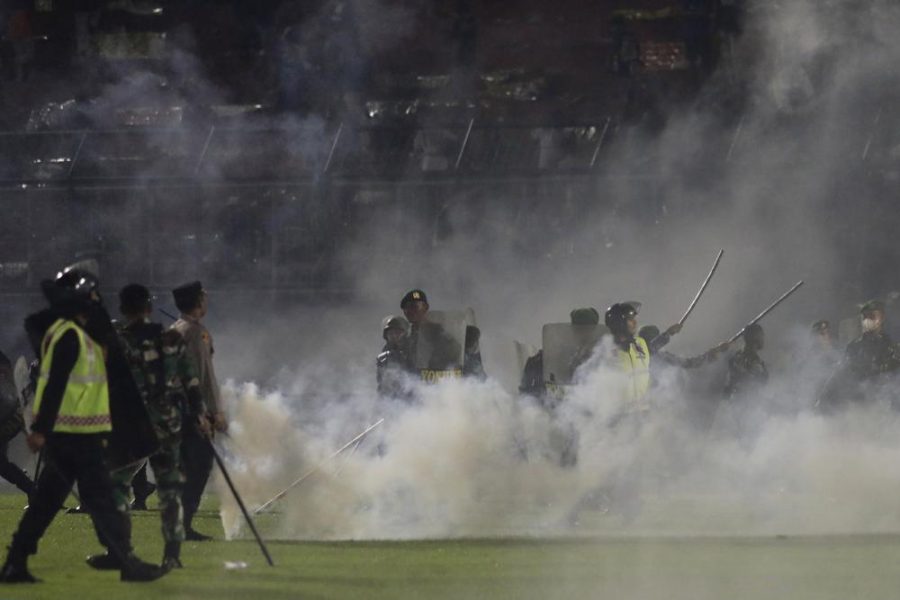 People swarm the field as tear gas is thrown at a soccer game (photo courtesy AP News).