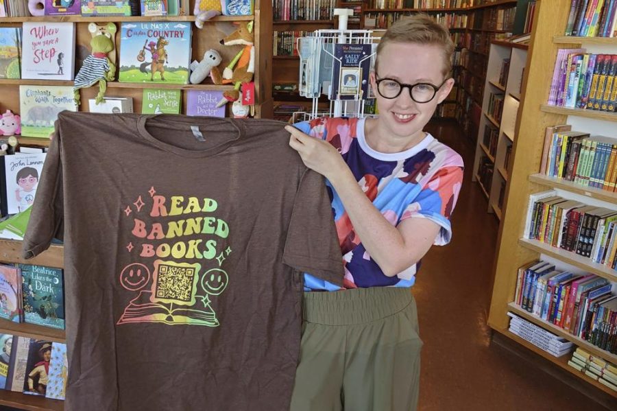 Summer Boismier holds up a shirt with a QR code that will take those who scan it to the Brooklyn Public Library (photo courtesy AP News).