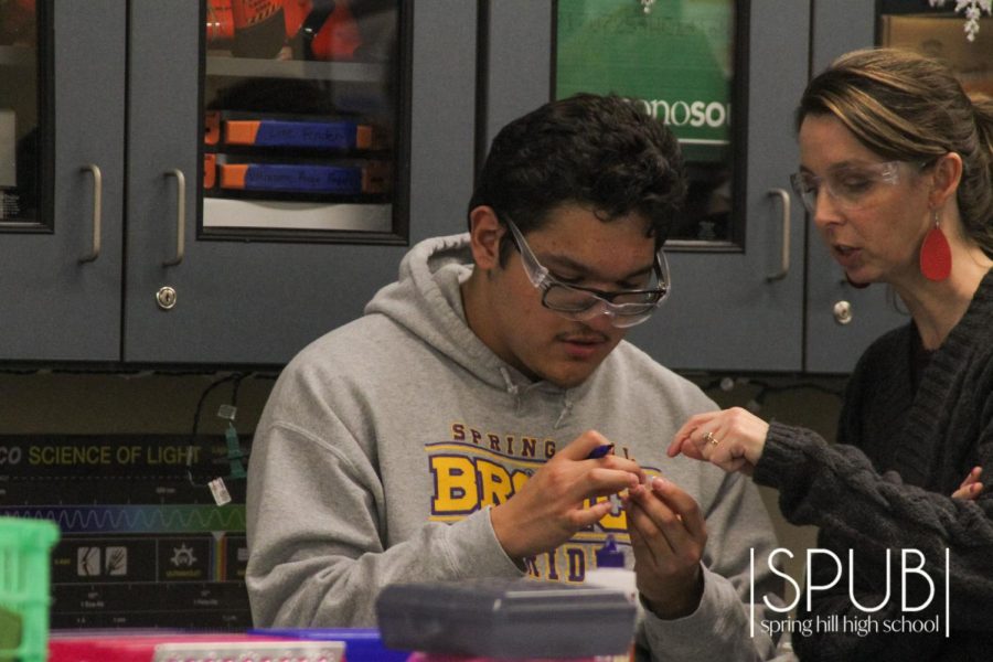 On Feb. 13, Melissa Reinhart helps chemistry student Adiel Garcia, 11, to remark measurements lines on a pipette that will later by lit as apart of their Chemistry rocket lab project.