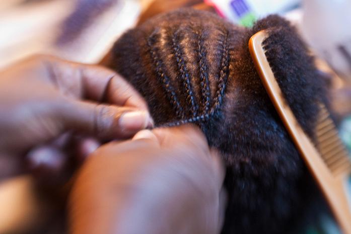 Child is getting their hair done in a traditional braiding style. These types of hair styles shouldnt cause a problem legally, however some schools ignore the CROWN Act (S. Depolo). 