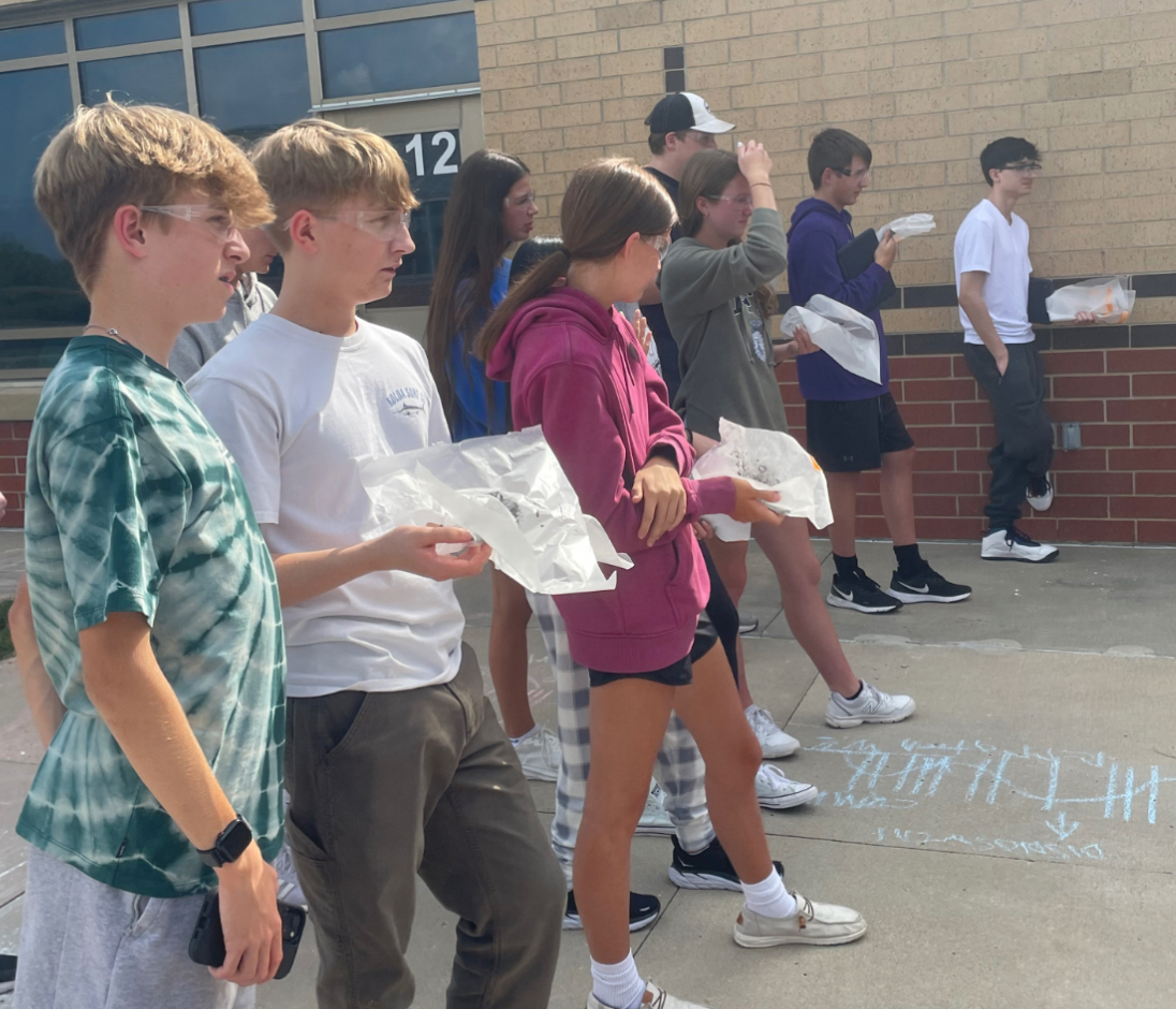 Students in Honors chemistry wait their turn to put their sparkler experiments to the test. They hope their experiment was completed correctly (Photo by Q. Harris). 
