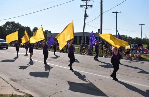 Multiple members of the color guard perform together in the yearly parade. Attending people watched from the side as they marched through the parade.  (Photo by A. Albright).