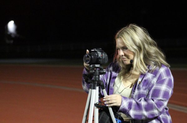 Ashlynn Watson, 12, records the homecoming football game from the end zone. Watson uses this footage to edit hype videos for the team (Photo by C. Bartek).
