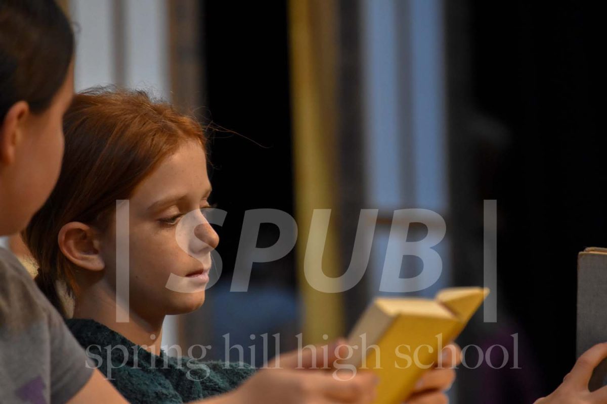 On Nov. 2, Students set up for a song with difficult choreography. Ava Copeland, 6, pulls out her prop and starts “reading” during the musicals second full run through. They were one of the few younger kids selected for this role.
