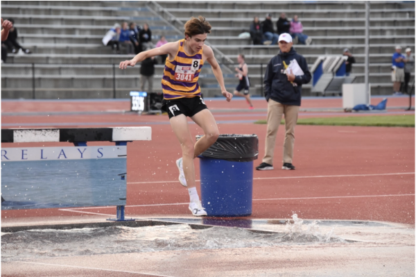 Jack Janovick, 12, jumps over the barrier into the water pit during the steeplechase at KU Relays. Janovick placed top eight, breaking a school record and bringing home a medal (Photo by D. Estes).
