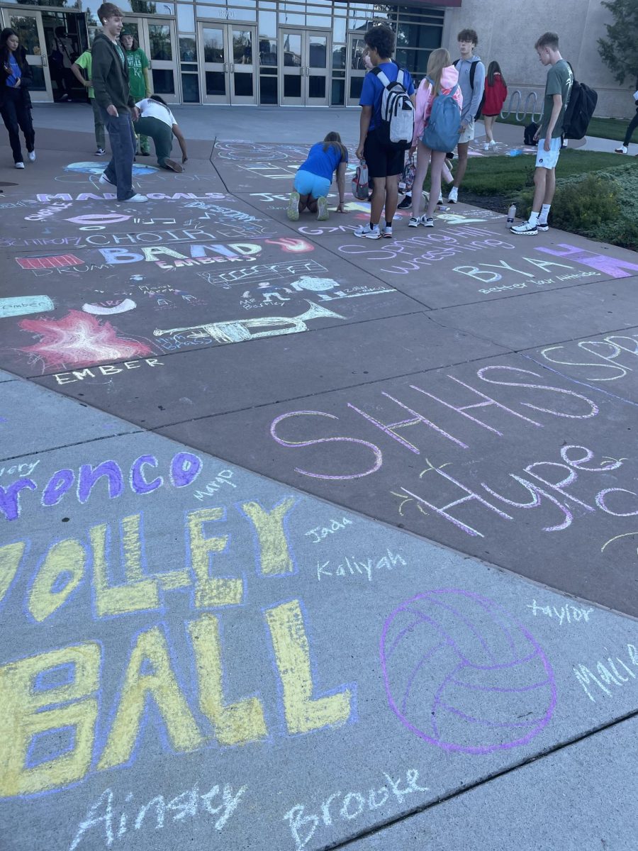 Students gather on the walkway entrance into the school to participate in chalk the walk. Every club and sport in the school has a square that they color to show support and spirit (Photo by Quorynn Harris).