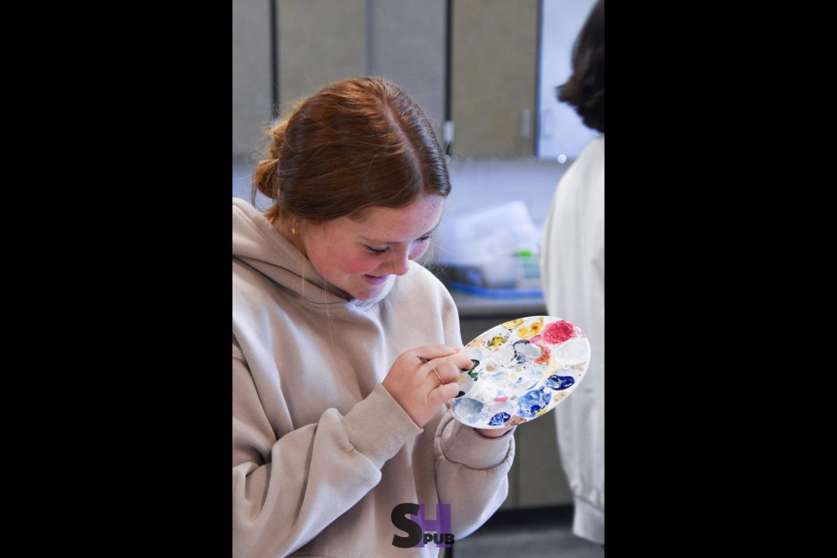 Emily Bellerive, 10, puts paint on their brush from their palette Oct. 31.