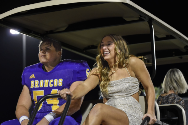 Logan Alexander, 12, and Margo Todd, 12, are carted onto the football field during coronation. The two were on a golf cart due to Todd’s surgery a few days prior. (Photo by O. Tarvin)