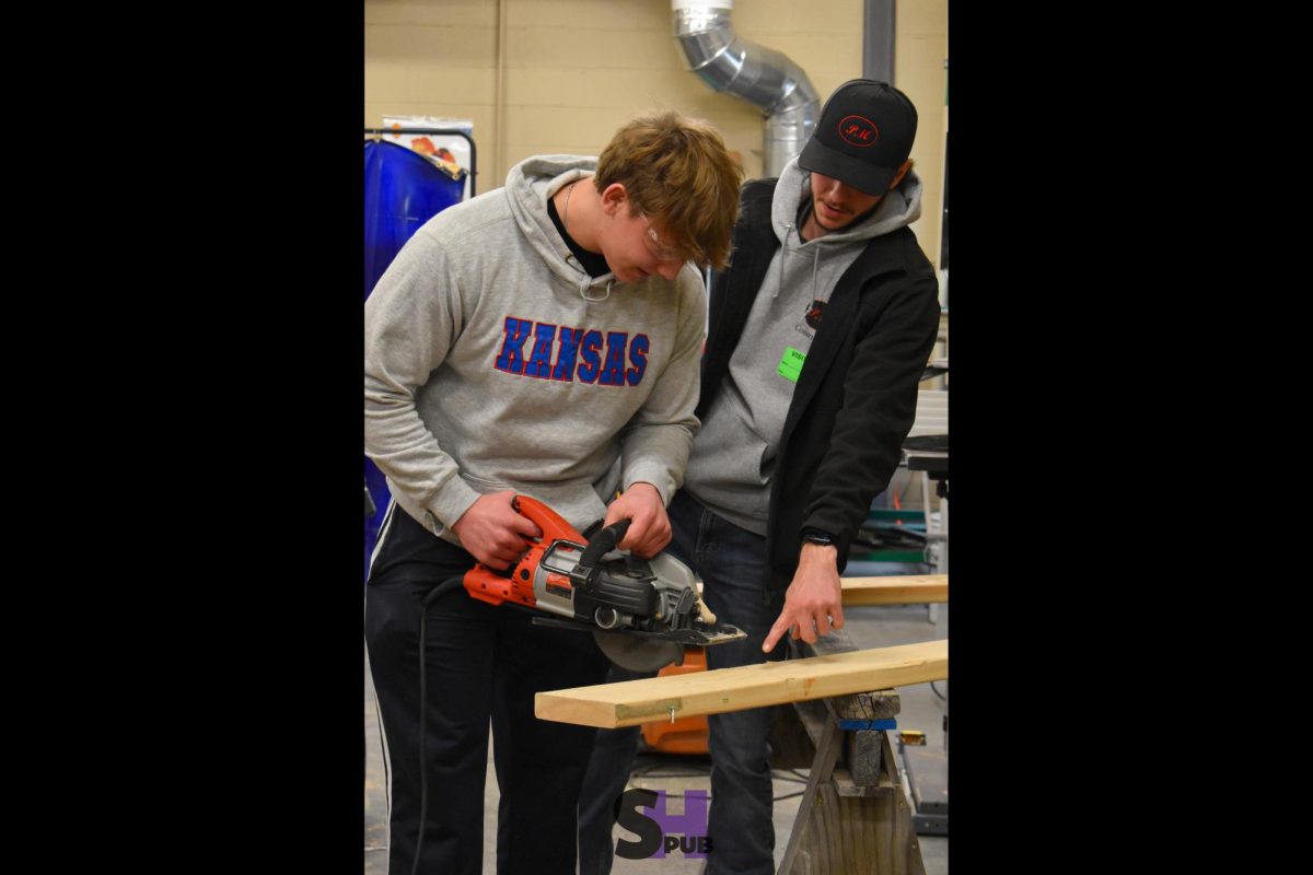 On Feb. 11, Cole Penhallow, 11, with the help of a guest speaker, uses a circular saw to cut through a plank of wood. 