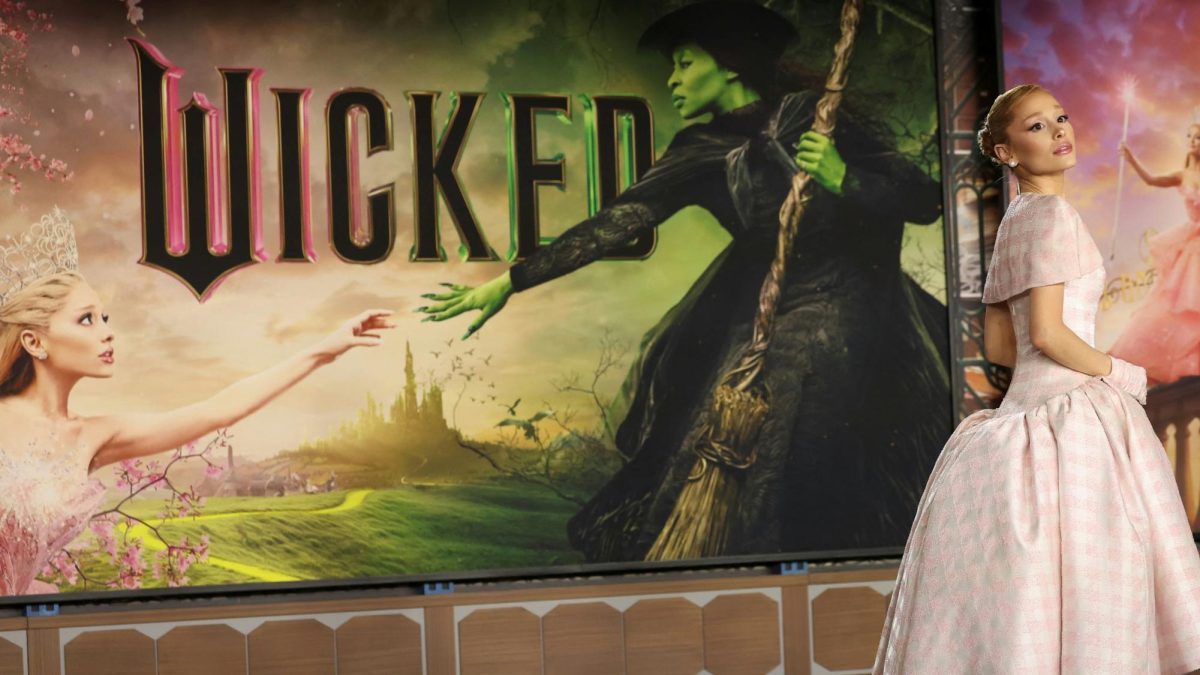 Ariana Grande posing by the Wicked: For Good premier poster.