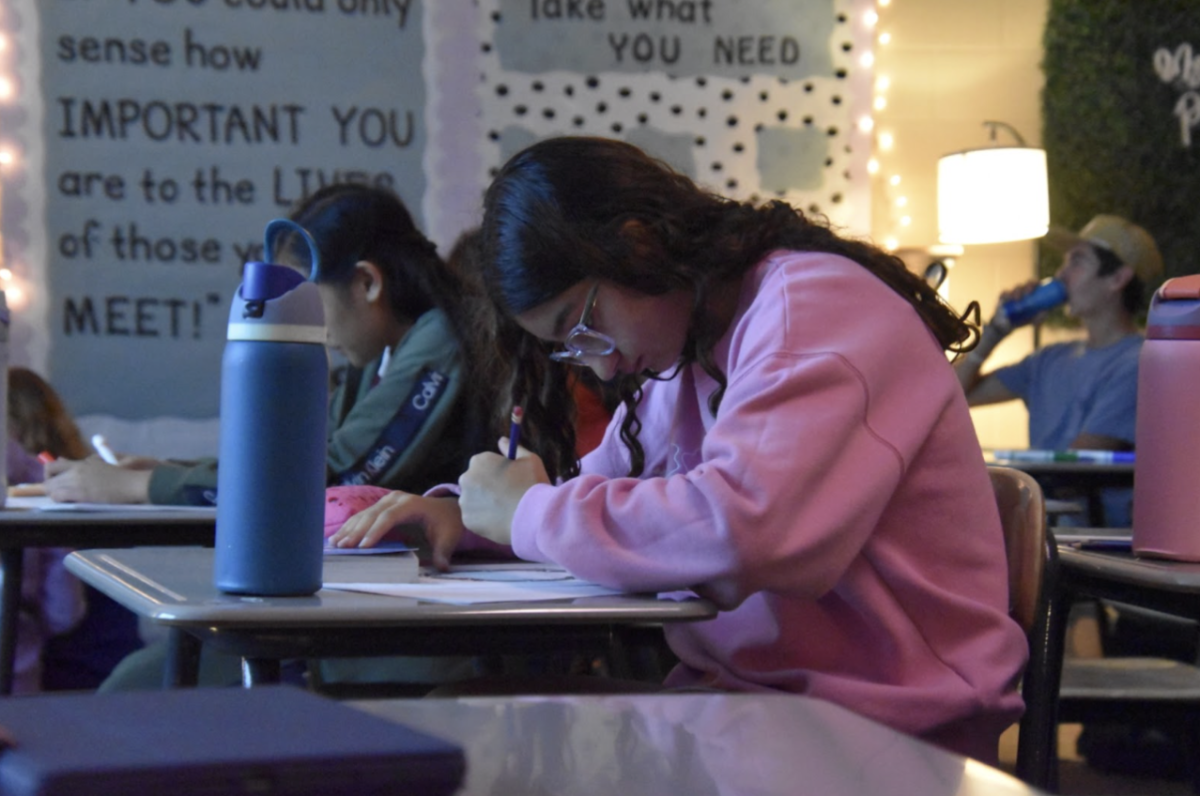 Pencil in hand and writing away, Mariana Asaad, 9, basks in the calming low light. In freshman english, with stories like The Odyssey and Romeo and Juliet, themes of death and conflict help keep students engaged.