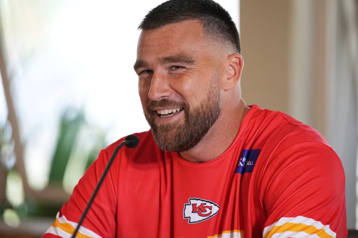 Kelce smiles while wearing Chiefs gear in his home.