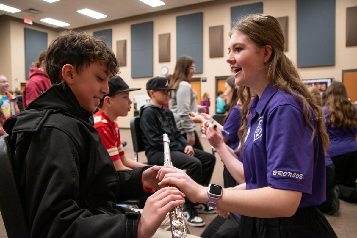Melanie Webber, 12, smiles and hands a flute to a fifth grader for fifth grade music recruitment day on Jan. 29.