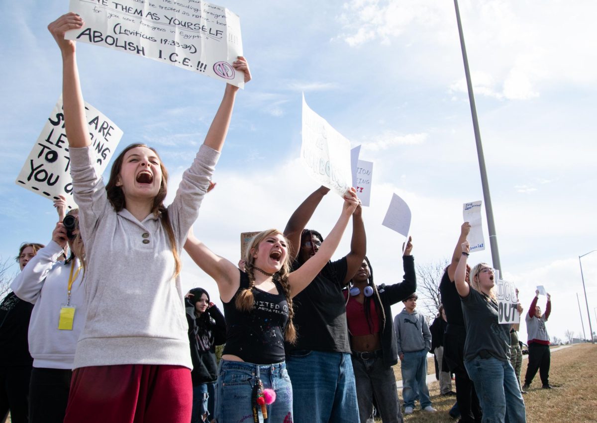 Several students hold up signs and shout as cars pass by on Ridgeview Rd. Many students came prepared with homemade signs, sharing with one another.