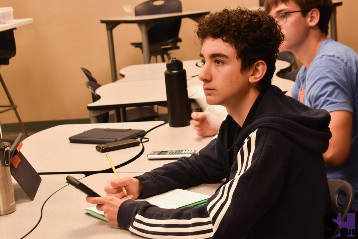 Alexander Bernd, 10, listens to Matthew Lundy, science teacher, explain a question on their chemistry worksheet on April 17.