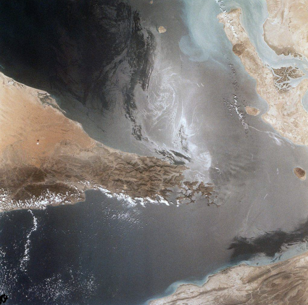 A satellite view shows swirling oil slicks and restricted ship traffic in the Strait of Hormuz amid rising conflict. The narrow passage between Iran and the Arabian Peninsula remains a critical choke point for global oil transport. 
